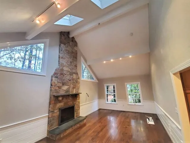 Vaulted great room with a stone fireplace and freshly painted walls