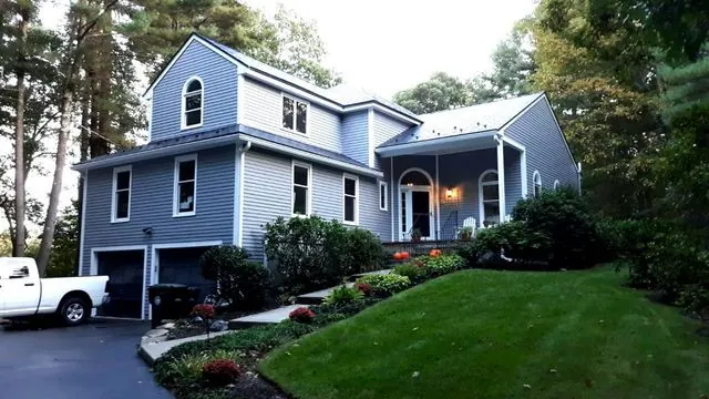Blue three-storey home with a wraparound porch, freshly painted