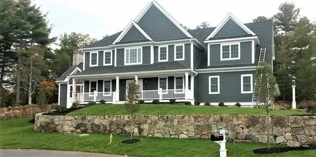 Large grey shingle-style home with a full-width covered porch