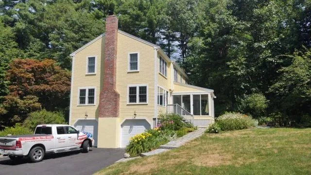 Butter-yellow colonial with a brick chimney after repainting