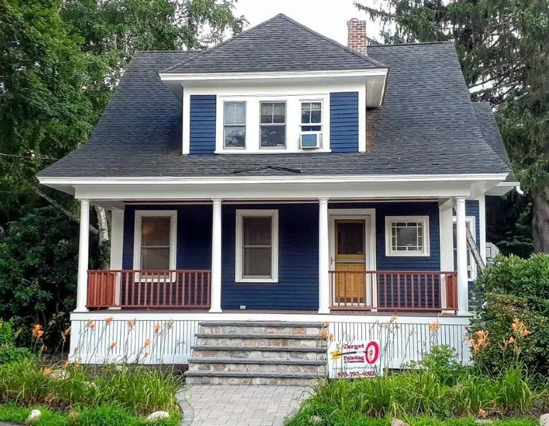 Navy bungalow with a white porch and repainted railings